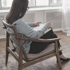 Emma Gerasimatos Individual Counselling Sydney’s Eastern Suburbs or Online A woman sitting in a wooden chair, wearing black trousers and a blue silk blouse. The woman is looking away from the camera, down at her notes. She has a pen in her hand. Emma is available for individual counselling in Coogee, Sydney’s Eastern Suburbs, or online.